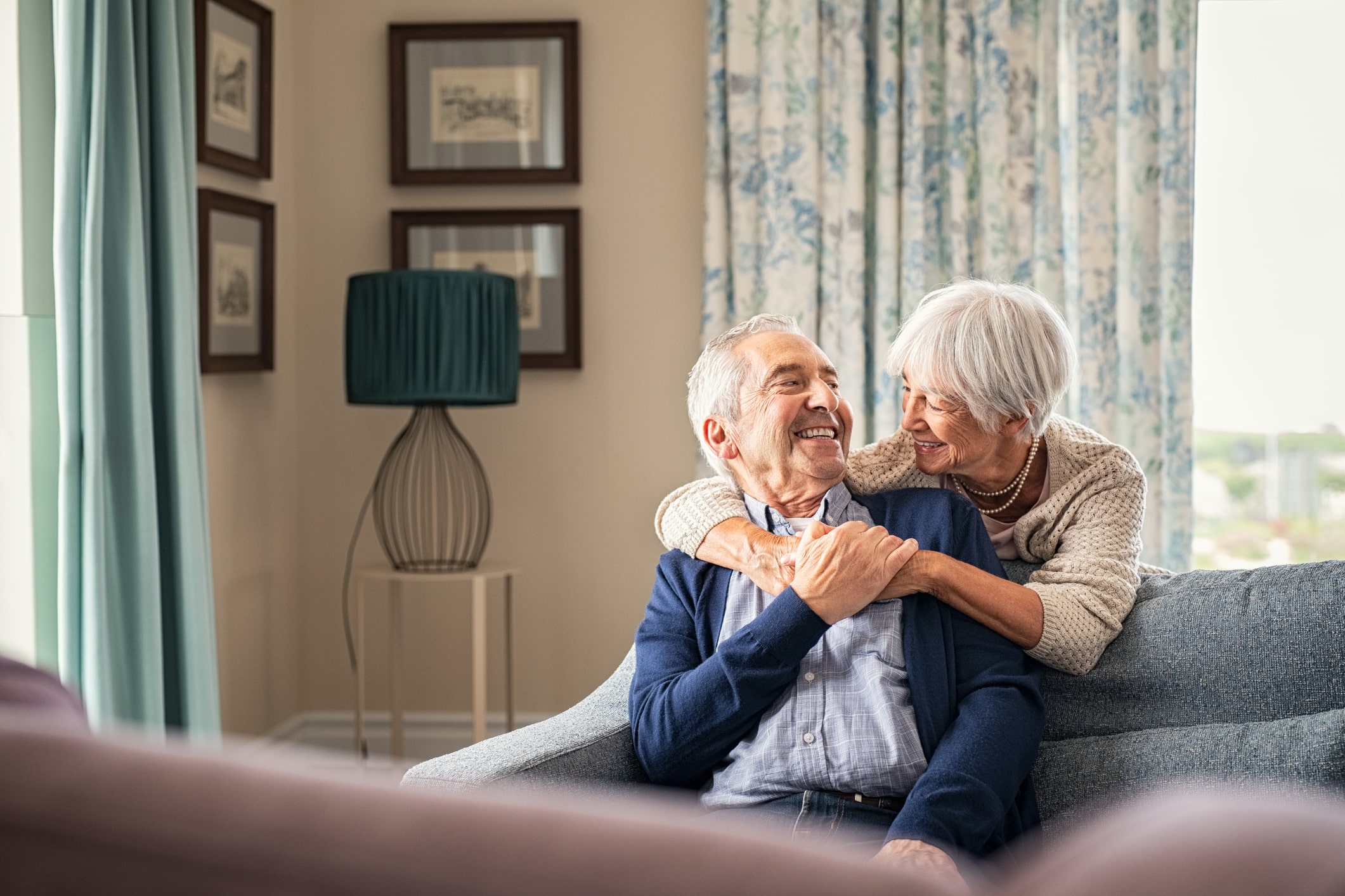 A happy elderly couple sitting on the couch after addressingsenior mental health in primary care
