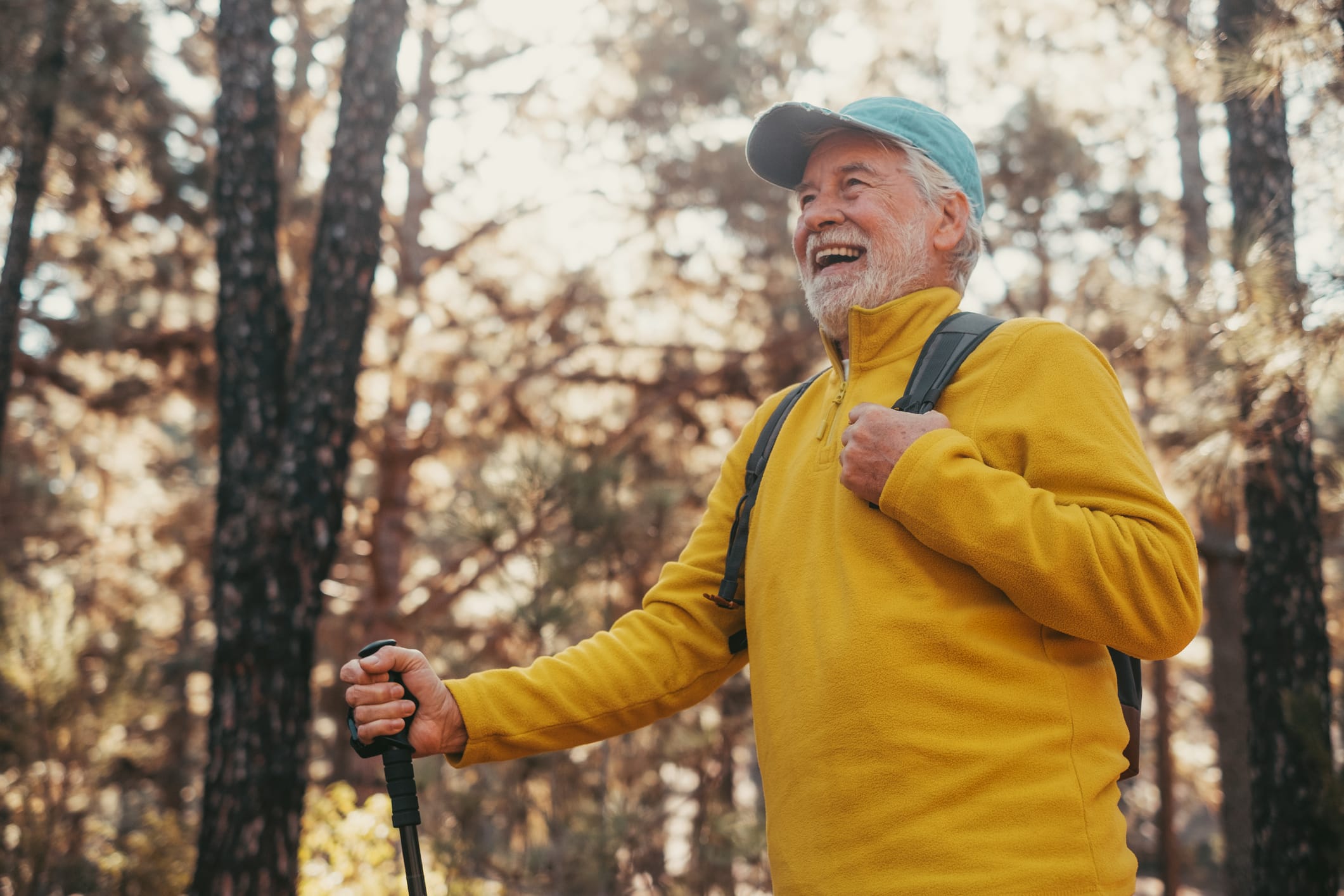 Older adult male hiking and smiling as he took proactive measures for chronic health conditions