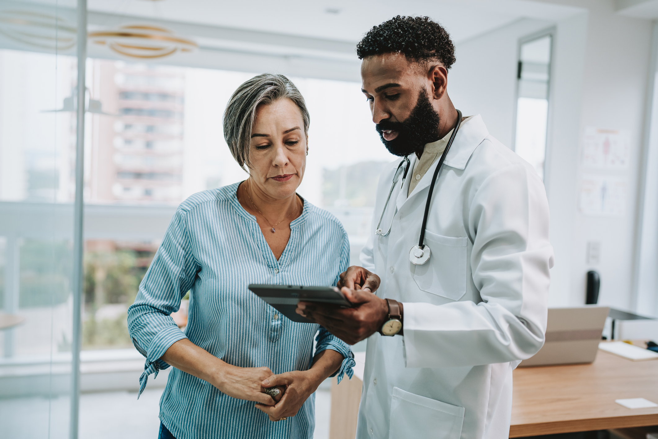 Doctor talking to patient holding digital tablet