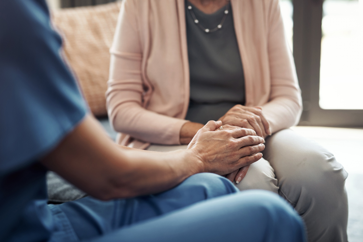 Cropped shot of an unrecognizable nurse sitting with her elderly patient and comforting her in a nursing home