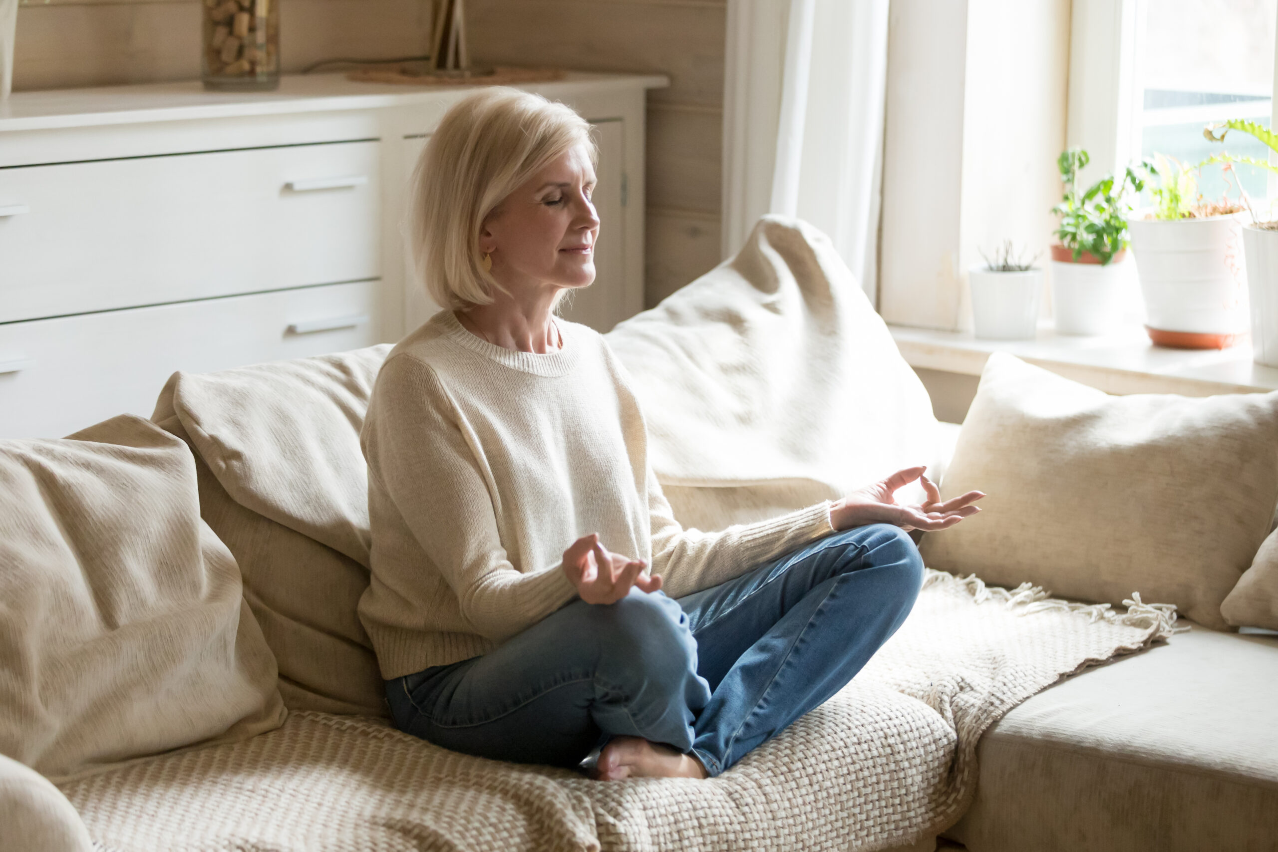 Mindful healthy mature woman practicing yoga meditation at home